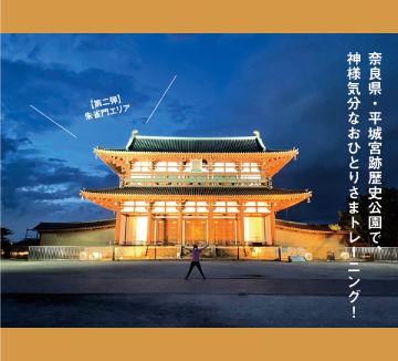 夕暮れにライトアップされた奈良県・平城宮跡歴史公園の朱雀門をバックに体操する女性の写真です。